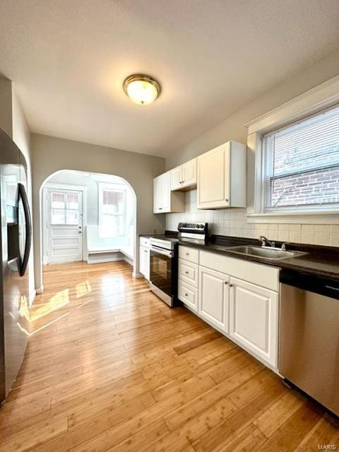 kitchen with light wood-type flooring, white cabinetry, sink, and appliances with stainless steel finishes