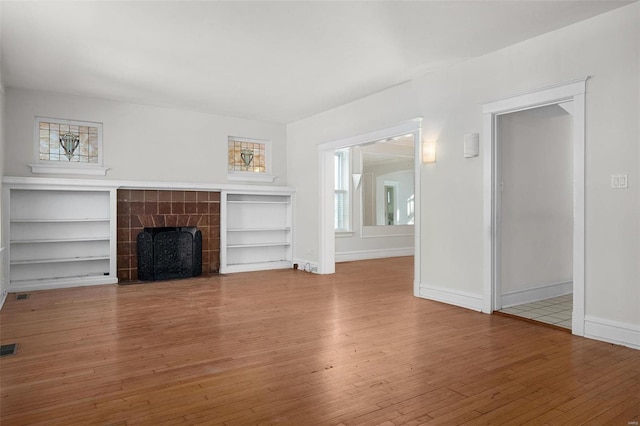 unfurnished living room featuring a tiled fireplace and wood-type flooring