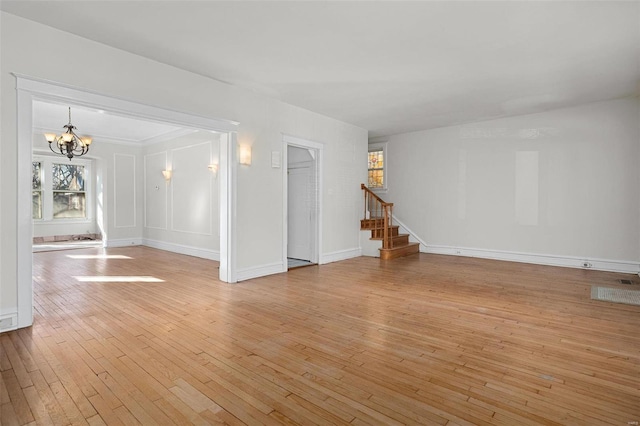 unfurnished room with an inviting chandelier and light wood-type flooring