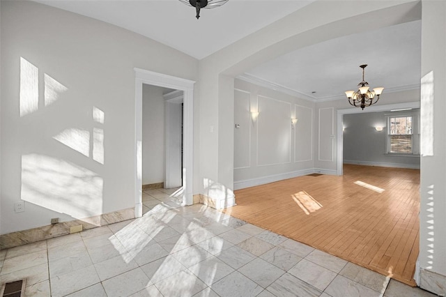 unfurnished room with a notable chandelier and crown molding