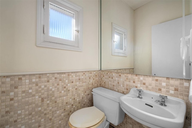 bathroom with toilet, sink, and tile walls