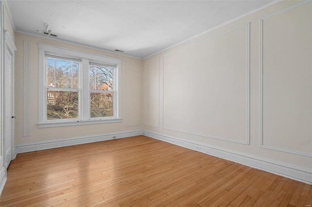 spare room with crown molding and light wood-type flooring