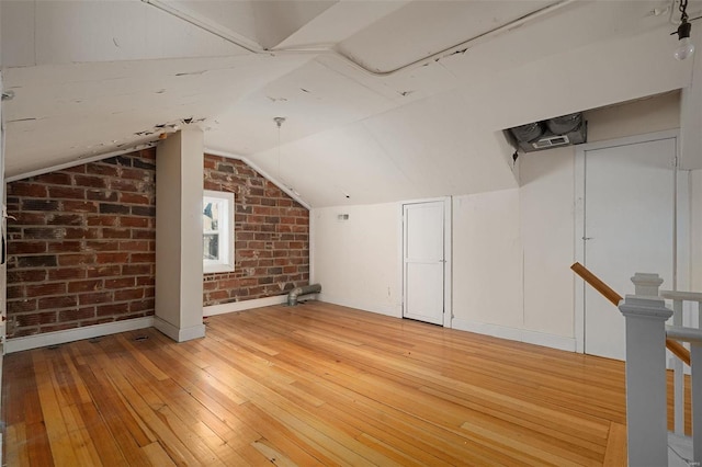 bonus room with vaulted ceiling, brick wall, and light hardwood / wood-style floors