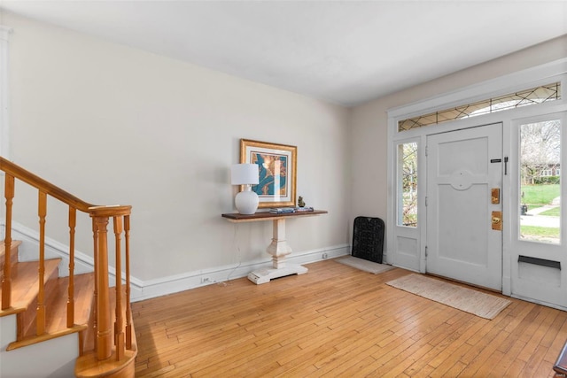 foyer with wood-type flooring, baseboards, and stairway