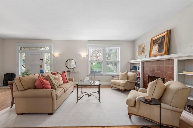 living room with baseboards, wood finished floors, and a tiled fireplace