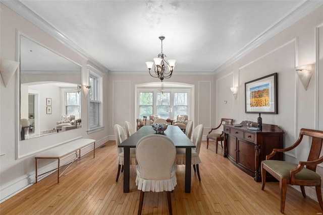 dining space with a notable chandelier, arched walkways, baseboards, light wood-style floors, and ornamental molding
