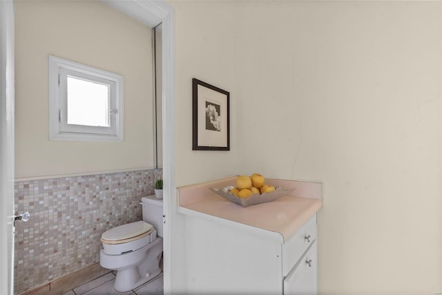 bathroom featuring tile walls, a wainscoted wall, toilet, and tile patterned flooring
