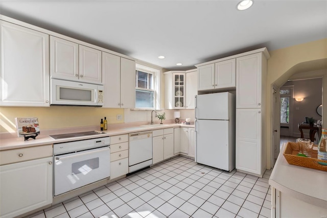 kitchen featuring white appliances, light countertops, arched walkways, and a sink