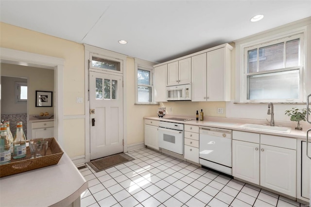 kitchen featuring white cabinetry, light countertops, a sink, and white appliances