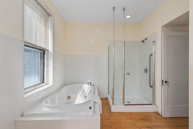 full bathroom featuring a stall shower, a wealth of natural light, wood finished floors, and a tub with jets