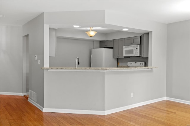 kitchen featuring gray cabinetry, hardwood / wood-style floors, white appliances, and sink