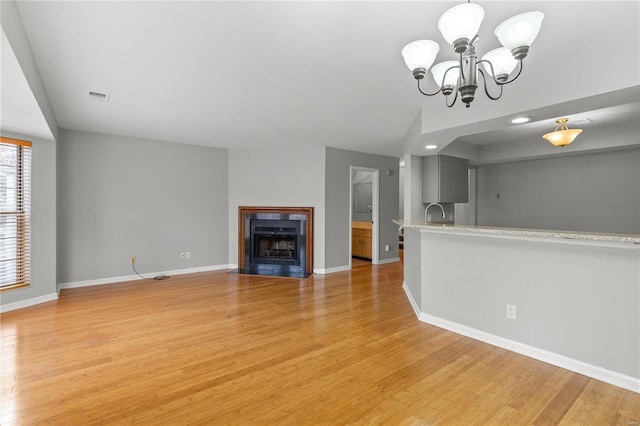 unfurnished living room with a chandelier and light hardwood / wood-style floors