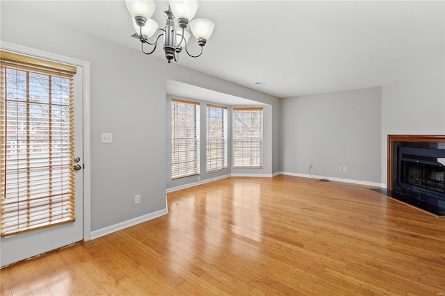 unfurnished living room featuring light hardwood / wood-style flooring and a chandelier