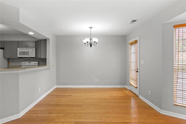 unfurnished dining area featuring light hardwood / wood-style floors and a notable chandelier