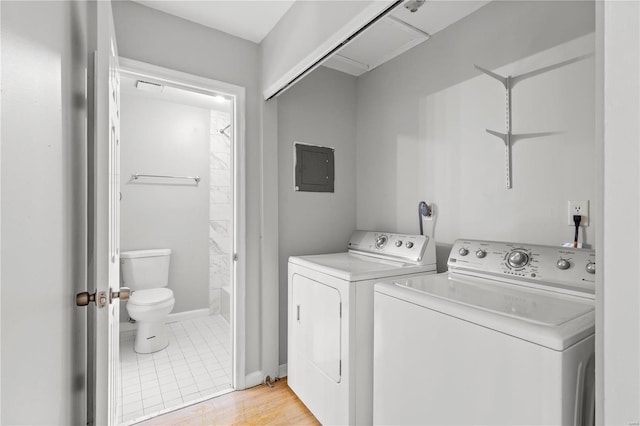 laundry area featuring electric panel, washer and dryer, and light wood-type flooring