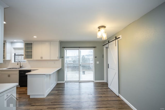 kitchen featuring a barn door, sink, white cabinets, and black dishwasher