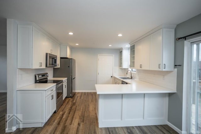 kitchen with kitchen peninsula, white cabinetry, dark hardwood / wood-style floors, and appliances with stainless steel finishes