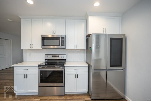 kitchen with white cabinets, appliances with stainless steel finishes, backsplash, and dark hardwood / wood-style flooring