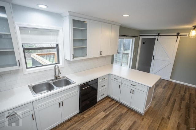 kitchen with white cabinets, a barn door, kitchen peninsula, and black dishwasher