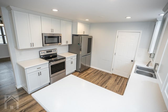 kitchen with stainless steel appliances, white cabinetry, dark hardwood / wood-style floors, and sink