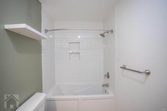 bathroom featuring tiled shower / bath combo and toilet