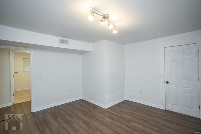 basement with rail lighting and dark wood-type flooring