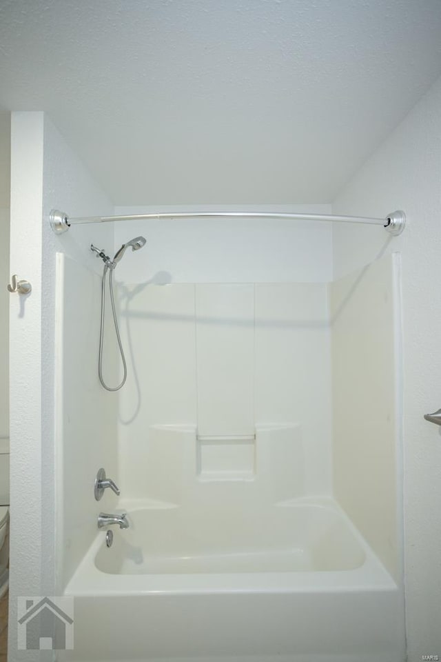 bathroom with bathing tub / shower combination and toilet