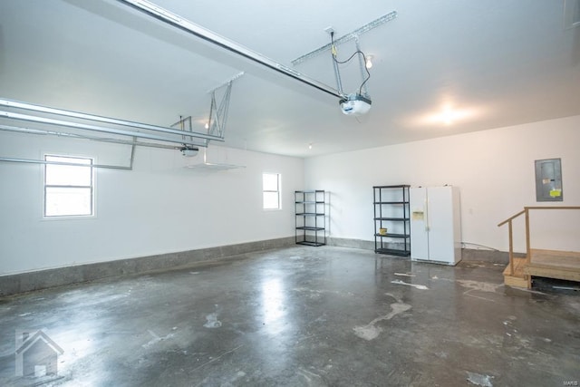 garage featuring electric panel, white fridge with ice dispenser, and a garage door opener