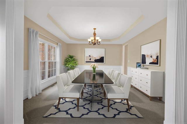 dining area with a raised ceiling, light carpet, and an inviting chandelier