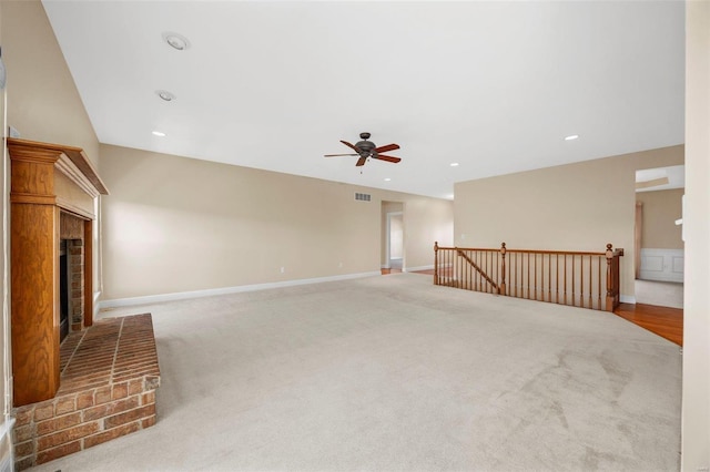 unfurnished living room with ceiling fan, a fireplace, and light carpet