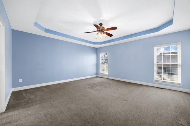 spare room with ceiling fan, carpet floors, and a tray ceiling