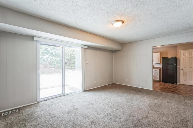 empty room with dark colored carpet and a textured ceiling