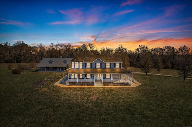 back house at dusk with a porch and a yard