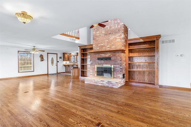 unfurnished living room featuring hardwood / wood-style floors, ceiling fan, and a brick fireplace