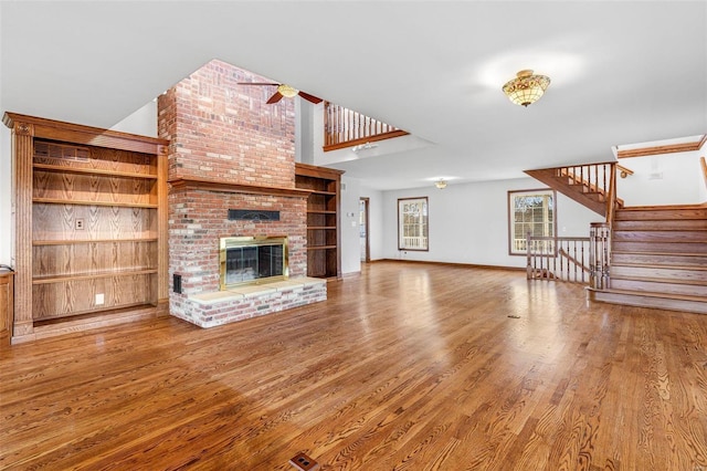 unfurnished living room featuring wood-type flooring and a brick fireplace