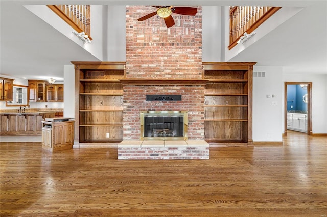 unfurnished living room with ceiling fan, a towering ceiling, and wood-type flooring