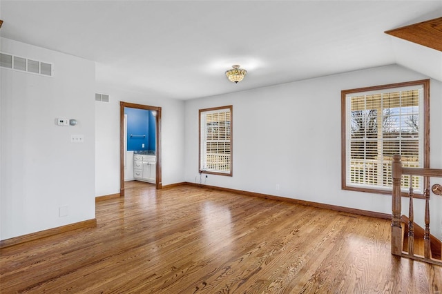 empty room with hardwood / wood-style floors and vaulted ceiling