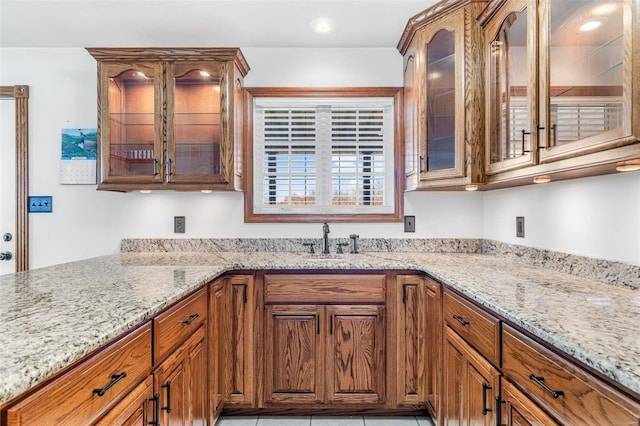 kitchen featuring light stone counters and sink