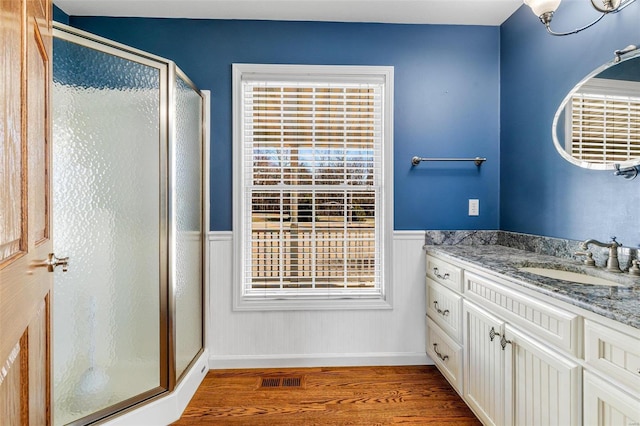 bathroom featuring wood-type flooring, vanity, a shower with door, and a notable chandelier