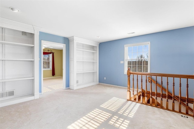 empty room featuring built in shelves and light colored carpet