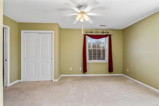 unfurnished bedroom featuring ceiling fan, light carpet, and a closet