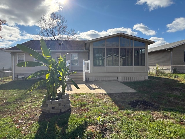 rear view of property with a yard, a patio area, and a sunroom