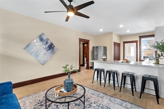 living room with ceiling fan and light hardwood / wood-style flooring