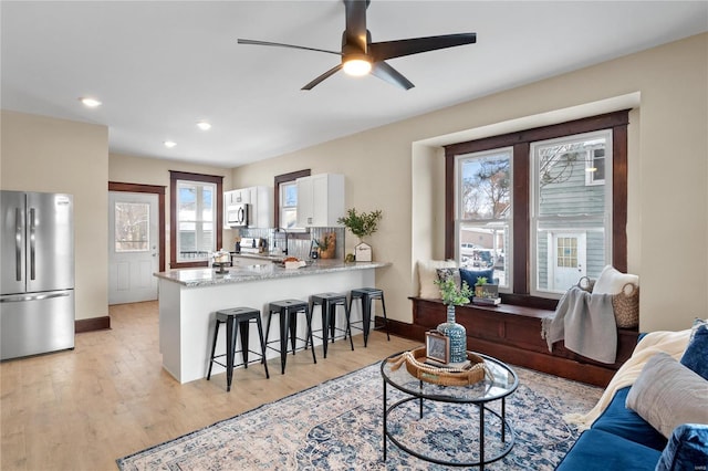 living room with light hardwood / wood-style floors and ceiling fan