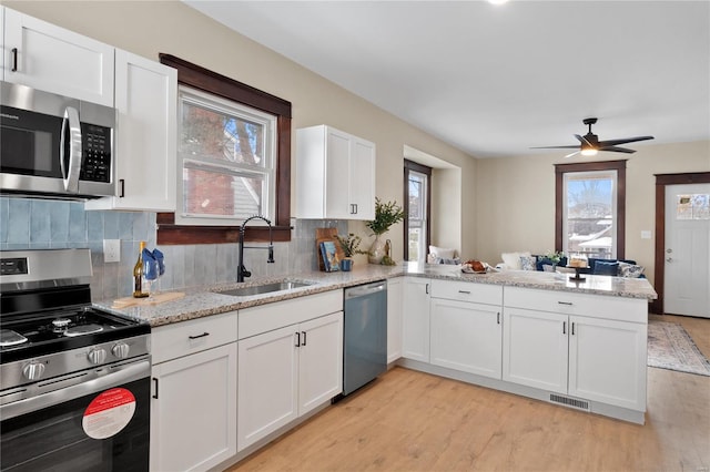 kitchen with backsplash, kitchen peninsula, white cabinetry, and appliances with stainless steel finishes