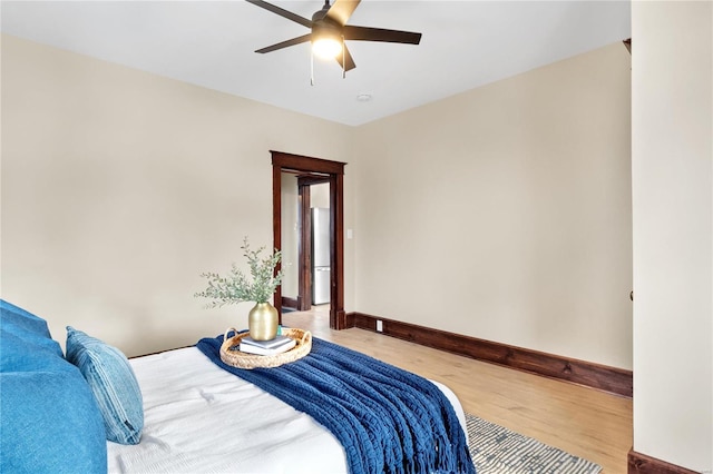 bedroom with light hardwood / wood-style flooring, ceiling fan, and stainless steel refrigerator