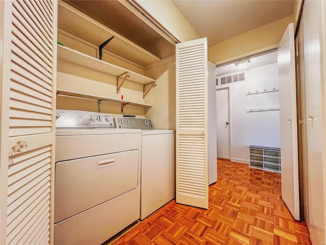 clothes washing area with washer and dryer and light parquet floors