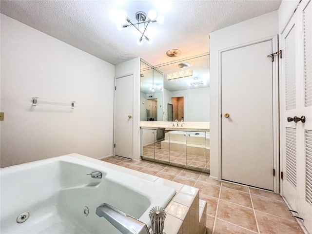 bathroom with tile patterned floors, a bathing tub, vanity, and a textured ceiling