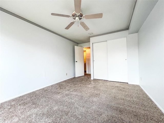 unfurnished bedroom featuring carpet, ceiling fan, crown molding, and a closet