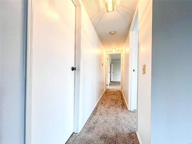 hall with light carpet and a textured ceiling